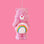 A pink care bear shaped glass ornament with a rainbow on it stomach. 