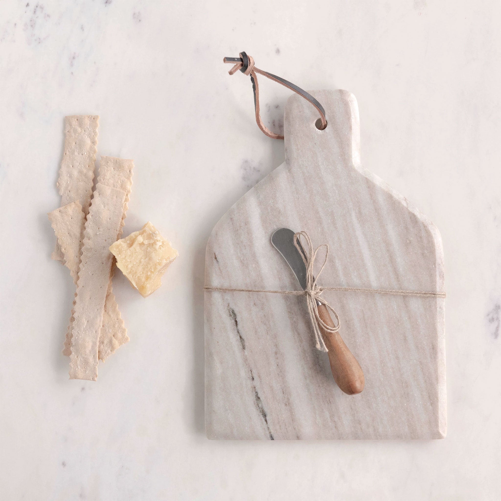 On an ivory background is a tan marble cutting board and knife tied to the center.