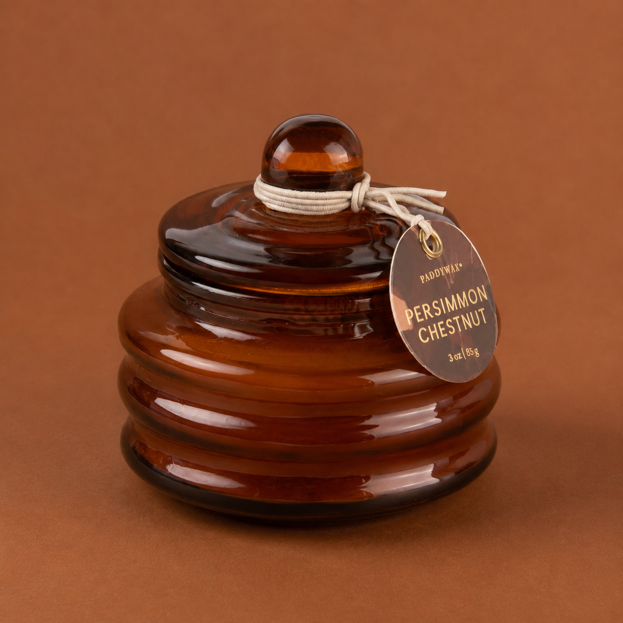 A brown glass candle with a lid. 