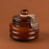 A brown glass candle with a lid. 