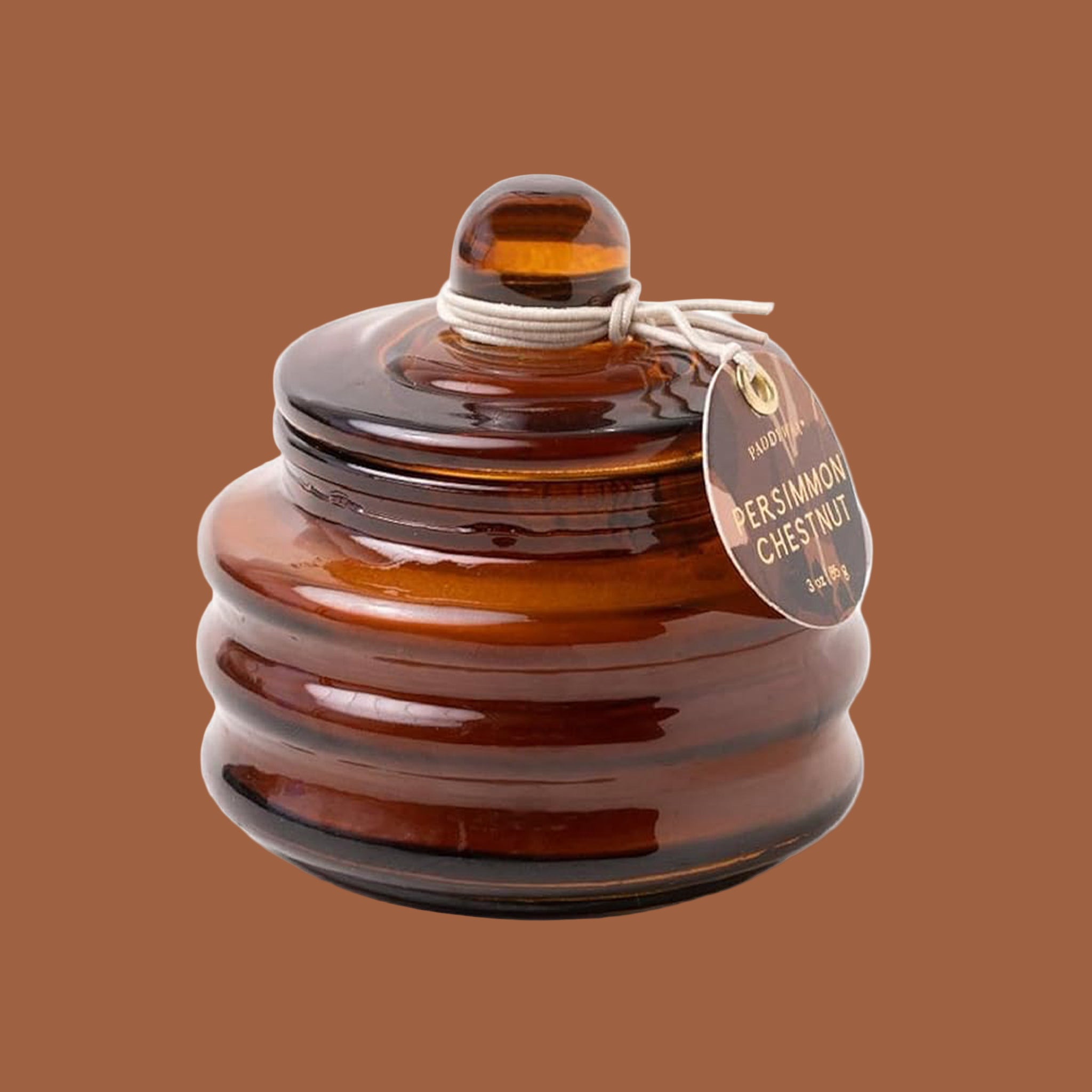 A brown glass candle with a lid. 