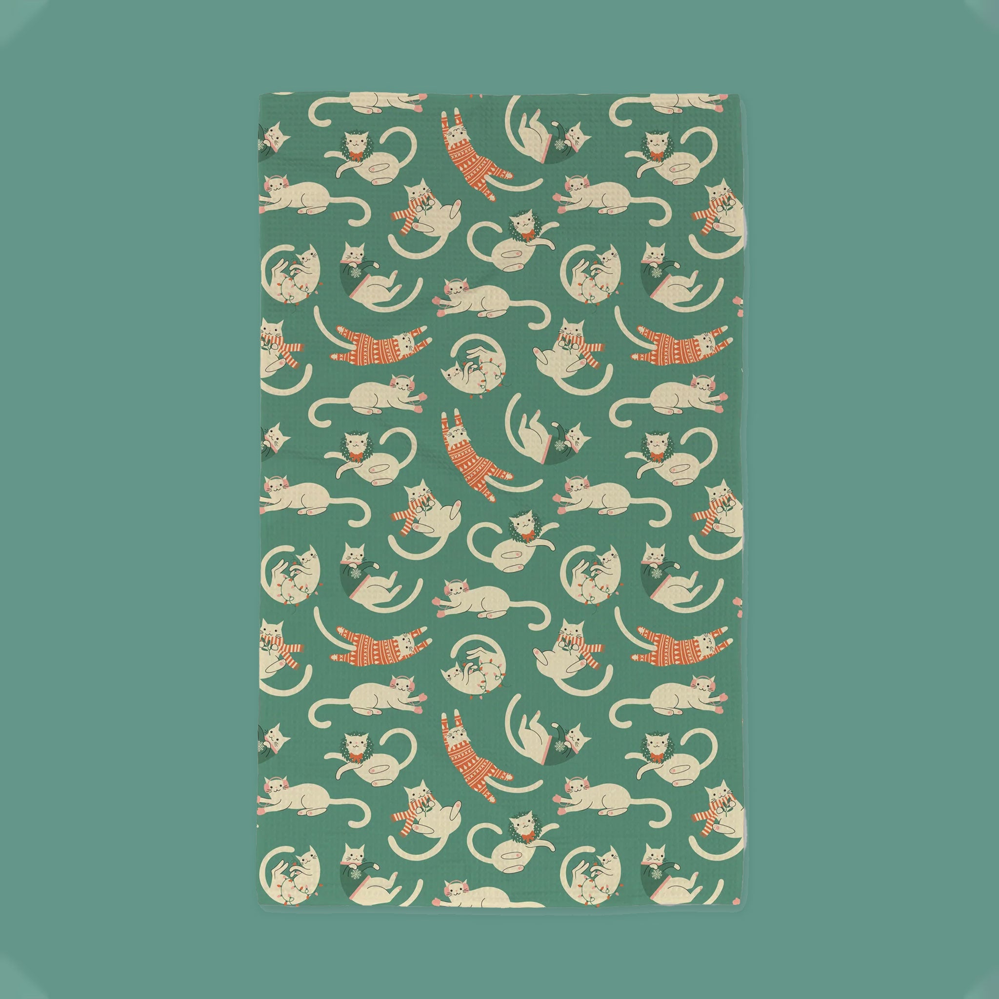 On a green background is a green waffle knit tea towel with a Christmas themed cats print.