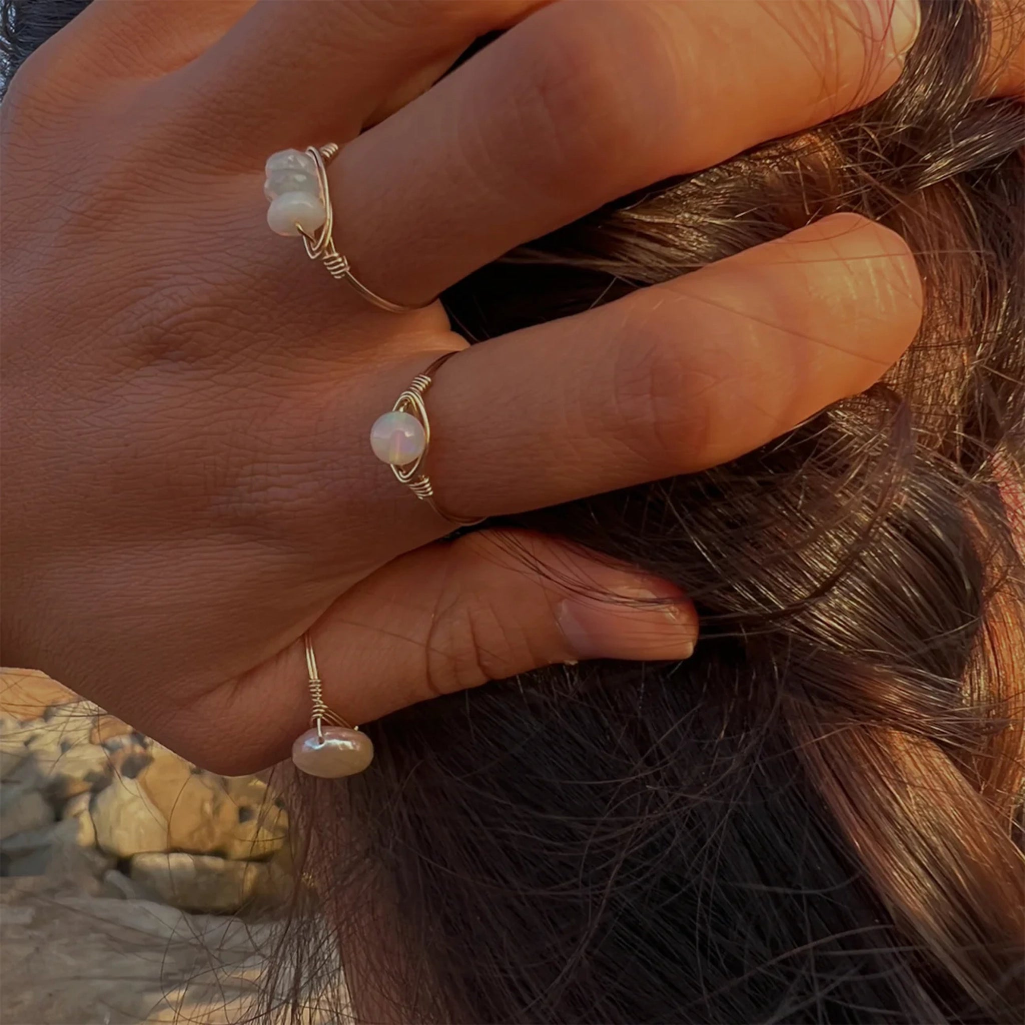 A gold ring, with a circle freshwater pearl in the center modeled on someones thumb in this photo. 