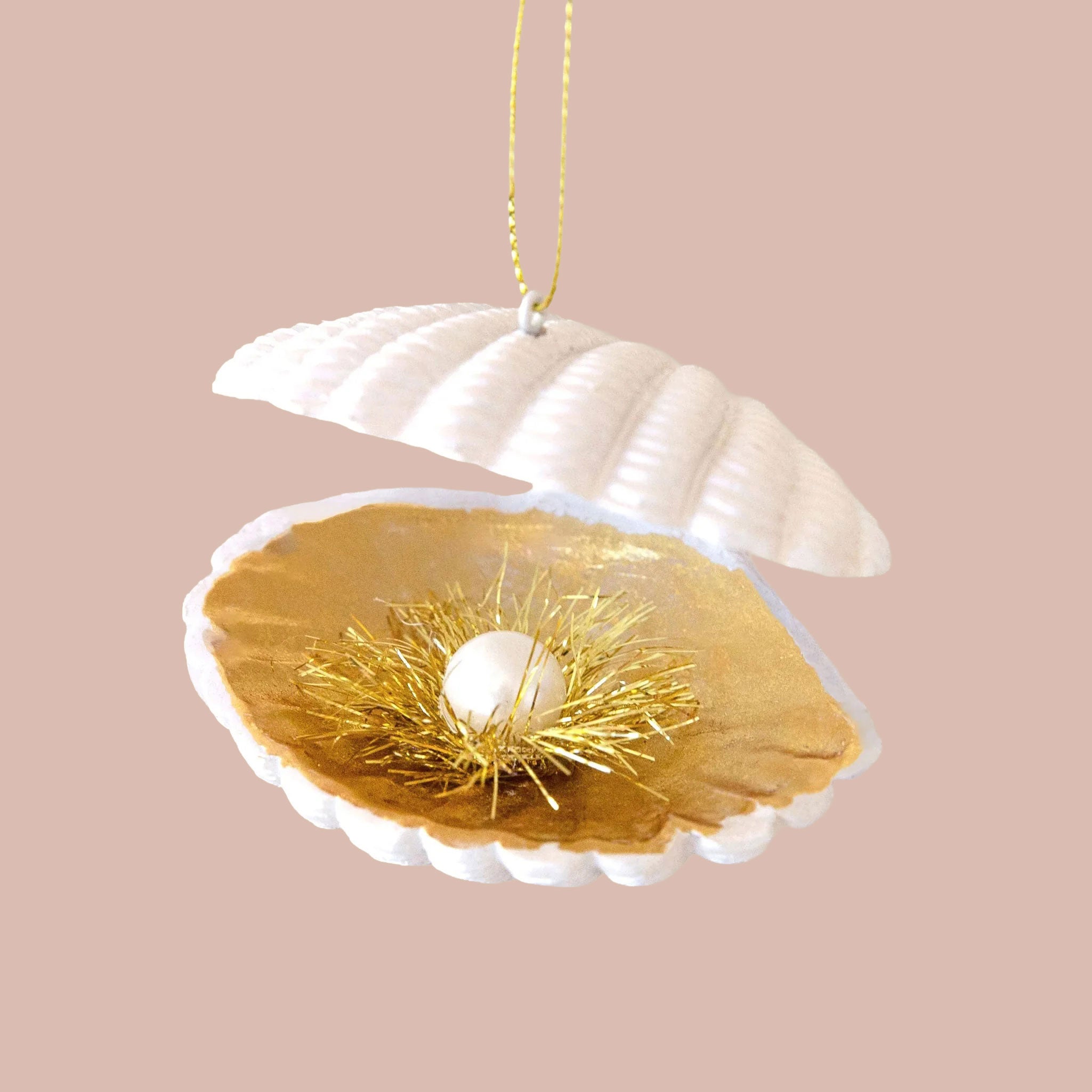 White clam ornament, with gold interior tinsel and a white faux pearl decoration inside of the clam. 