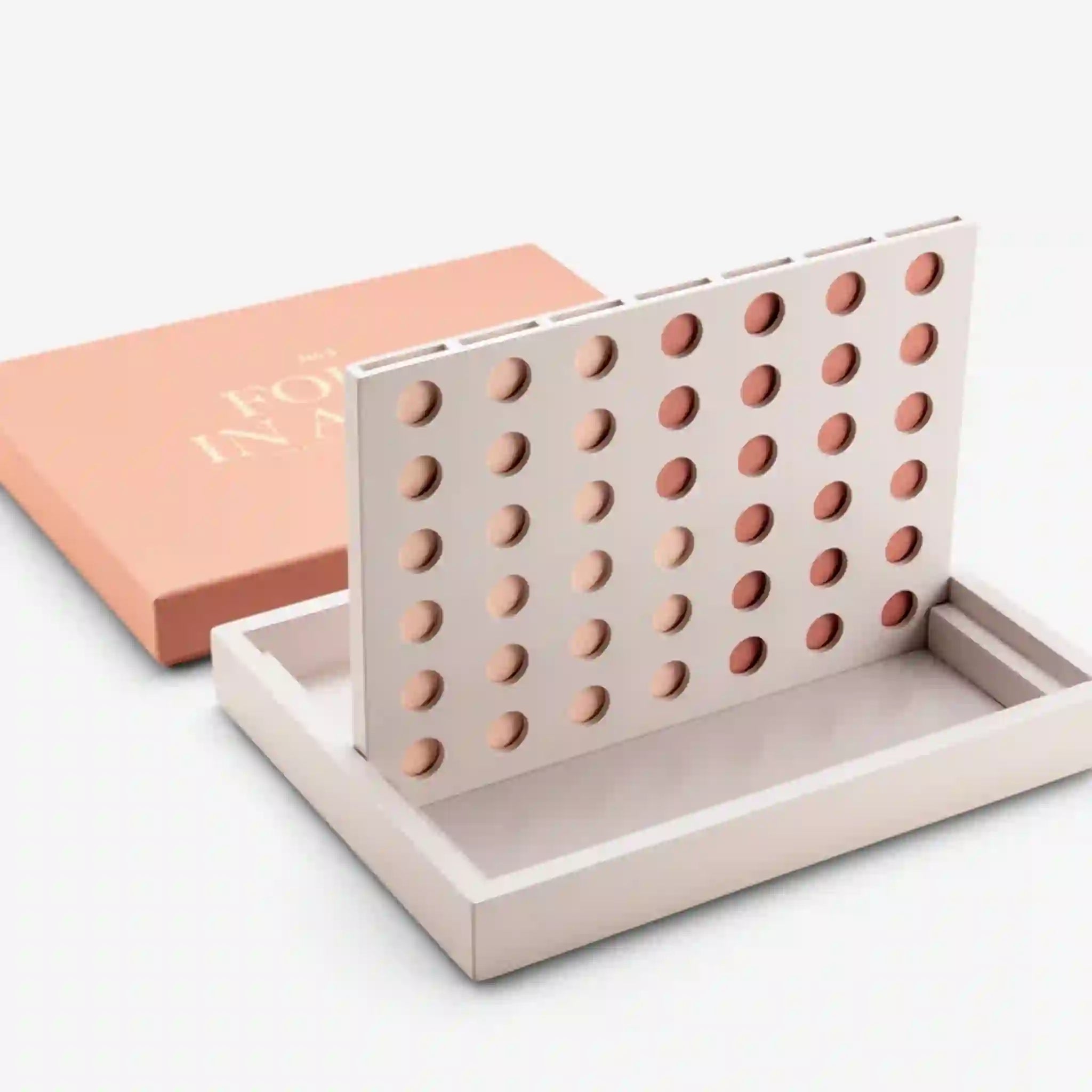 On a white background is a tan four in a row board game in a salmon pink box. 