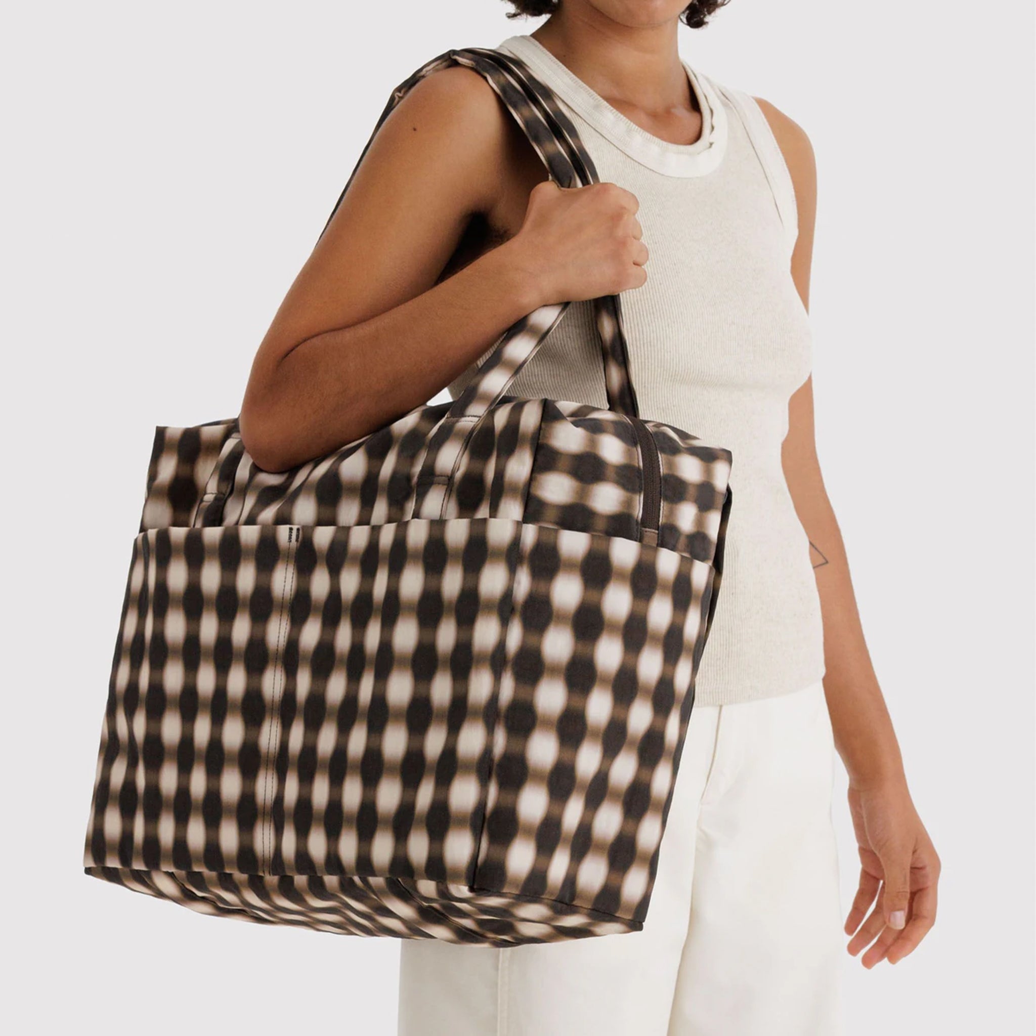 A blurred edge brown, black and tan gingham print nylon carry on tote. 