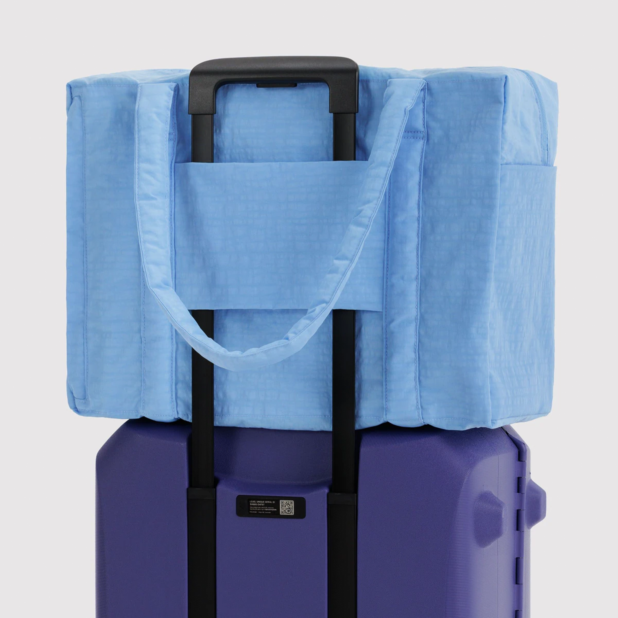 a powder blue nylon bag on top of a suitcase