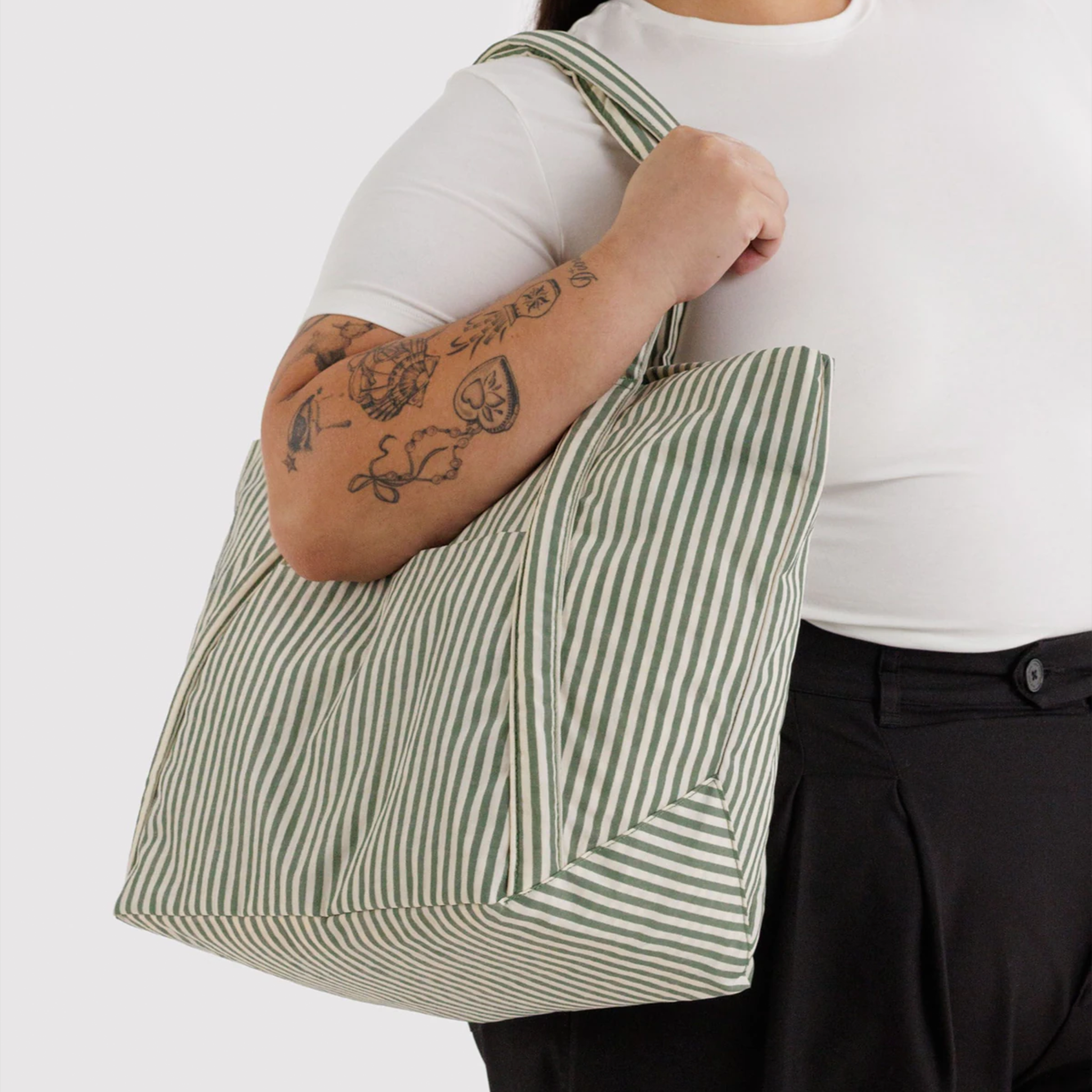 sage colored striped bag on a model's shoulder.