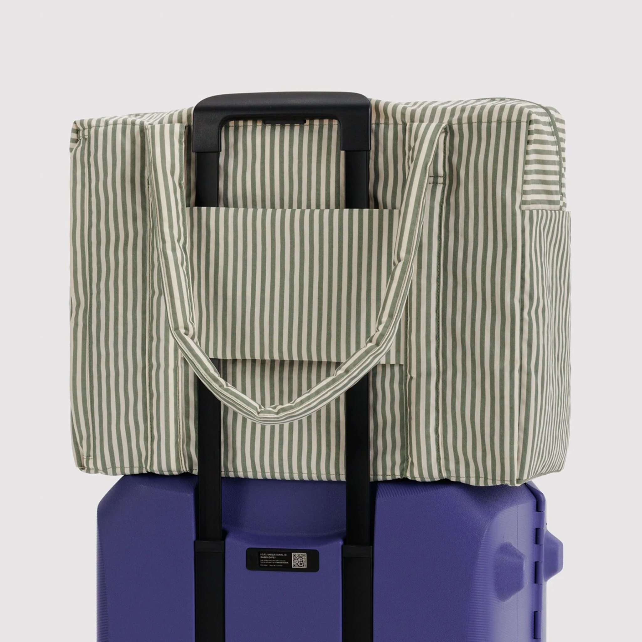 sage colored striped bag on blue suitcase.