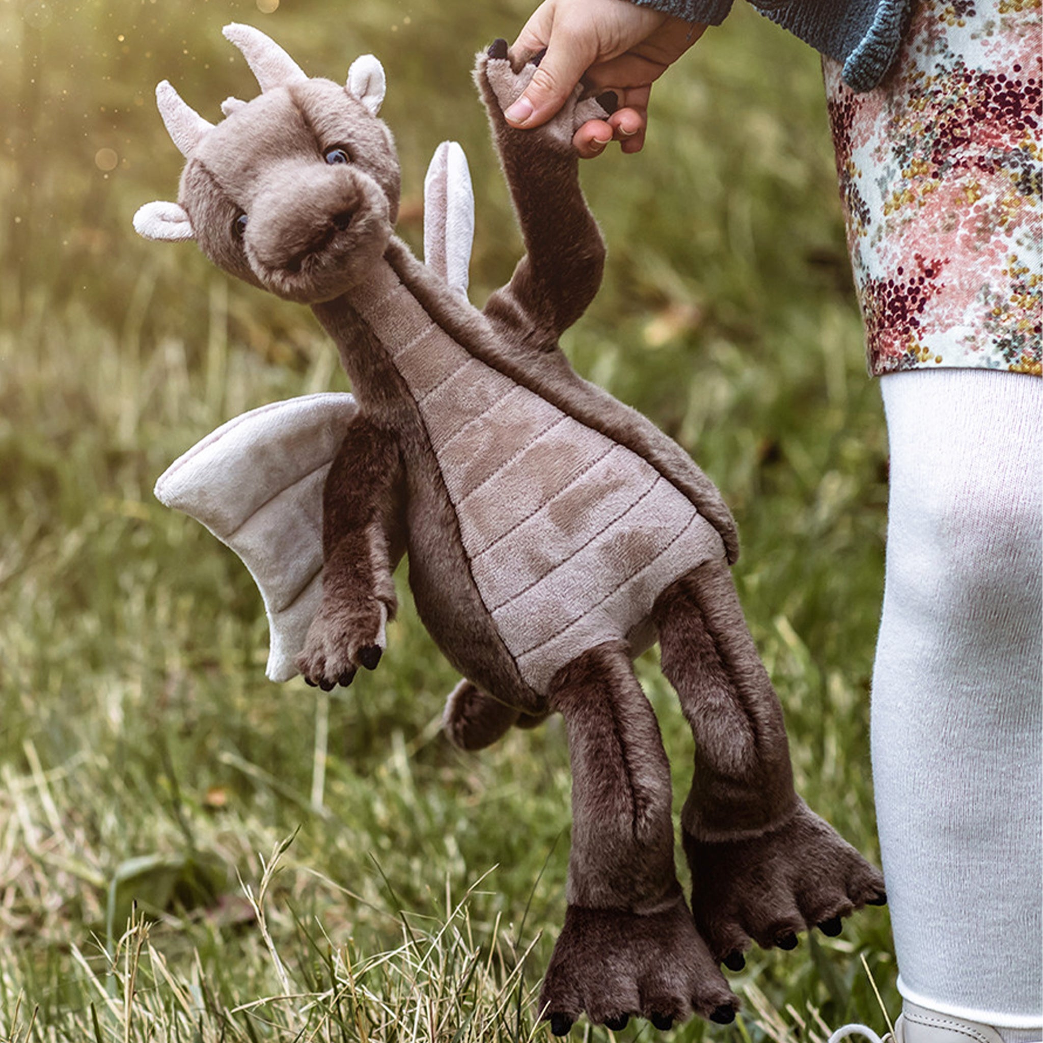 A greyish brown dragon shaped stuffed animal toy. 