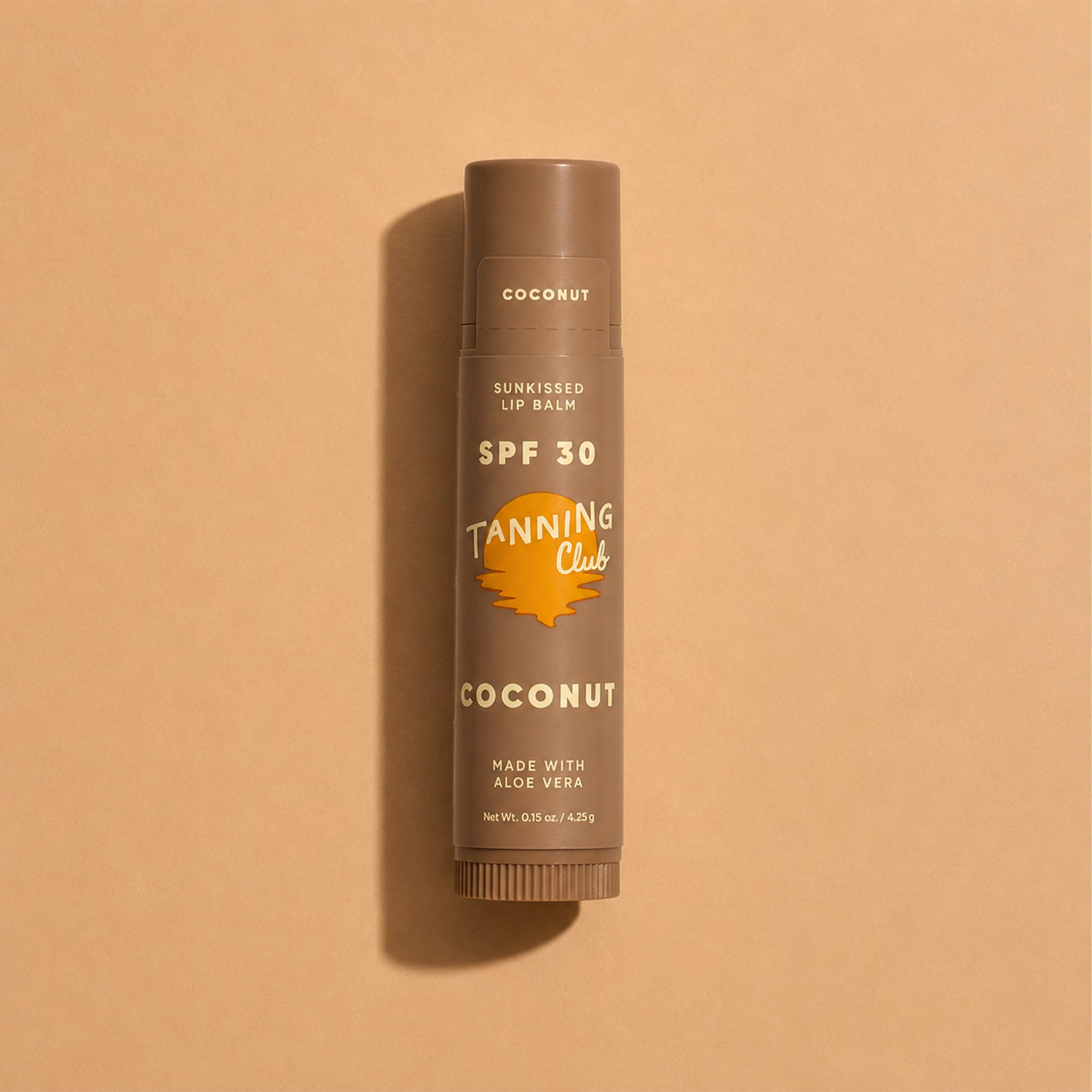 Tanning Club lip balm with SPF 30 on a beige background