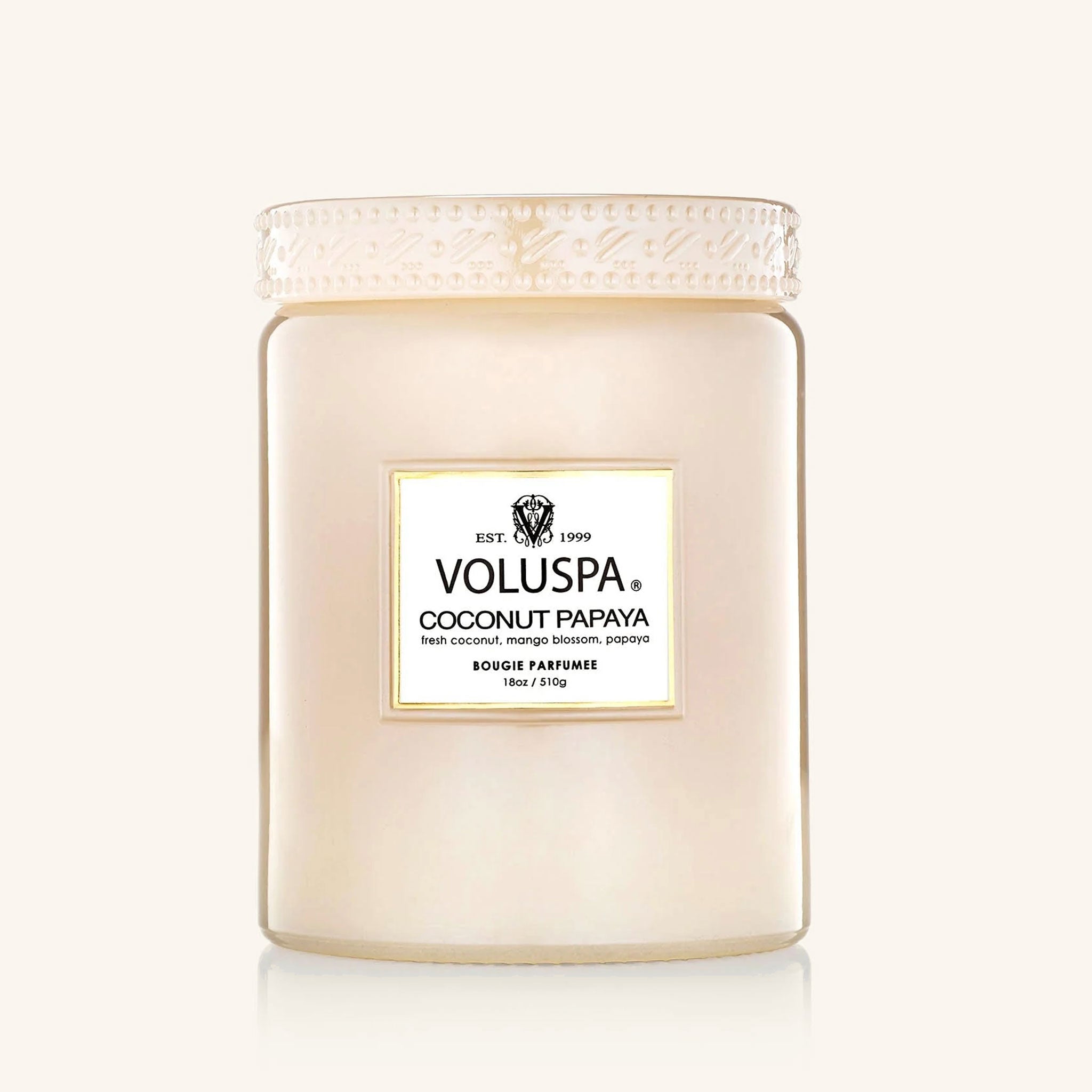 A soft pink glass jar candle sits in the middle of the image.  The candle label reads "Voluspa Coconut Papaya"