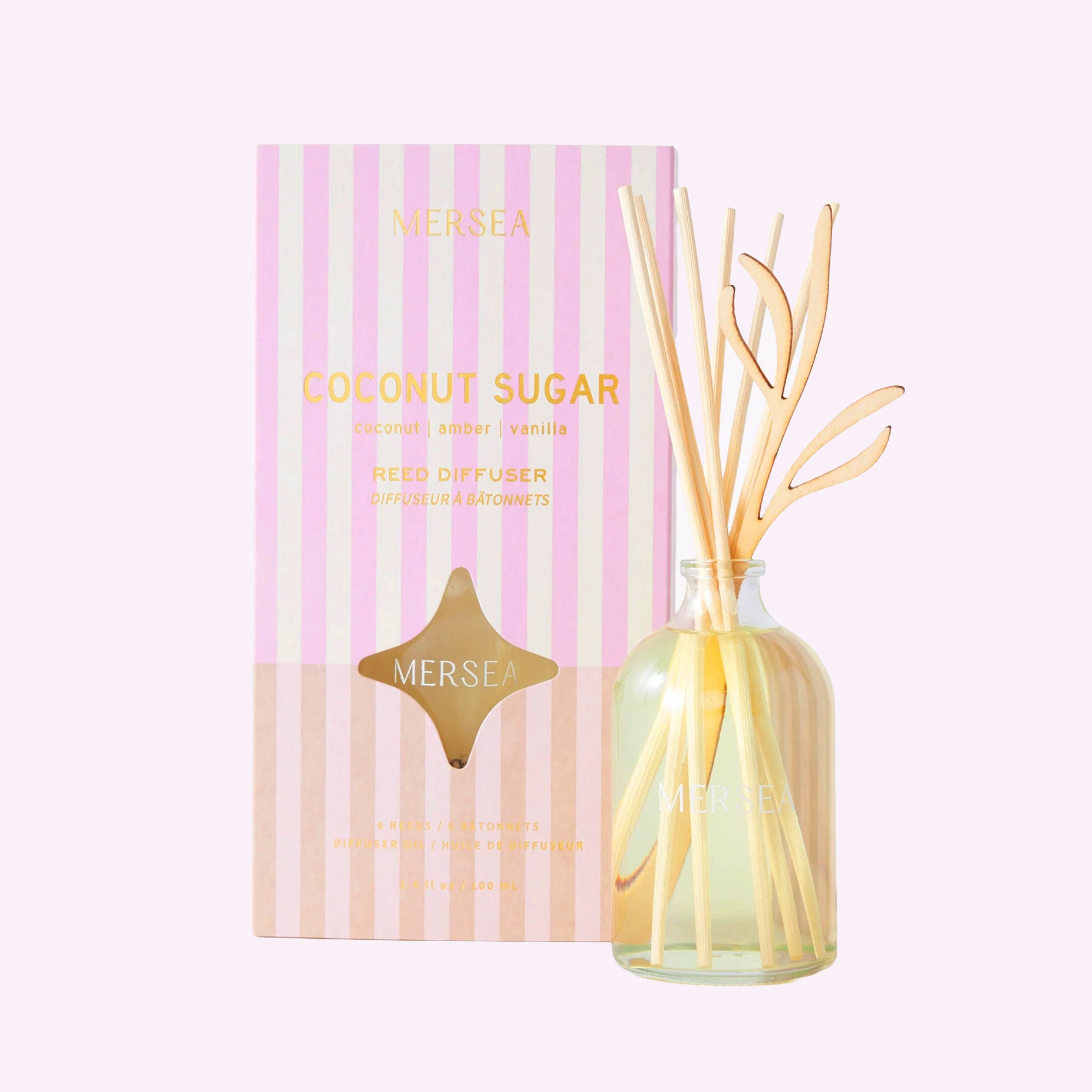 a pink and white striped box filled with a reed diffuser. 