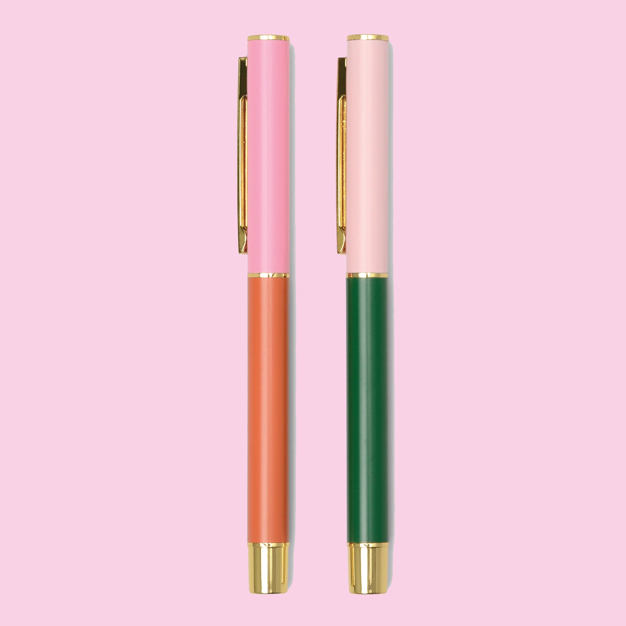 On a pink background is a pair of pens, one orange and pink and the other emerald green and pink. 