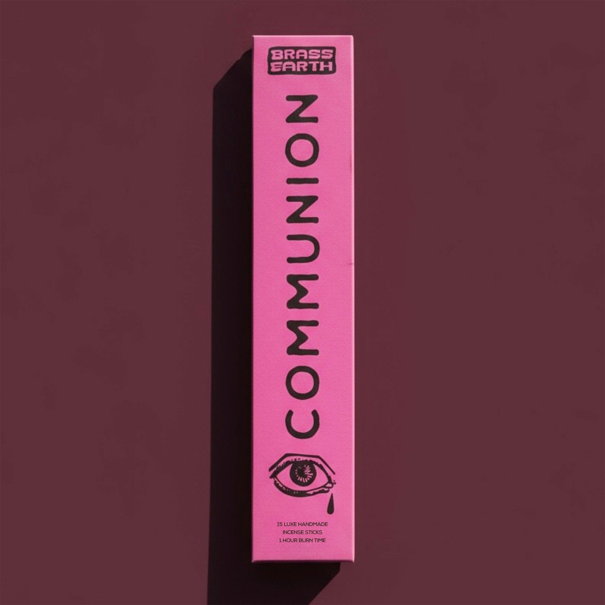 Pink box labeled 'Communion' by Brass Earth on a dark red background