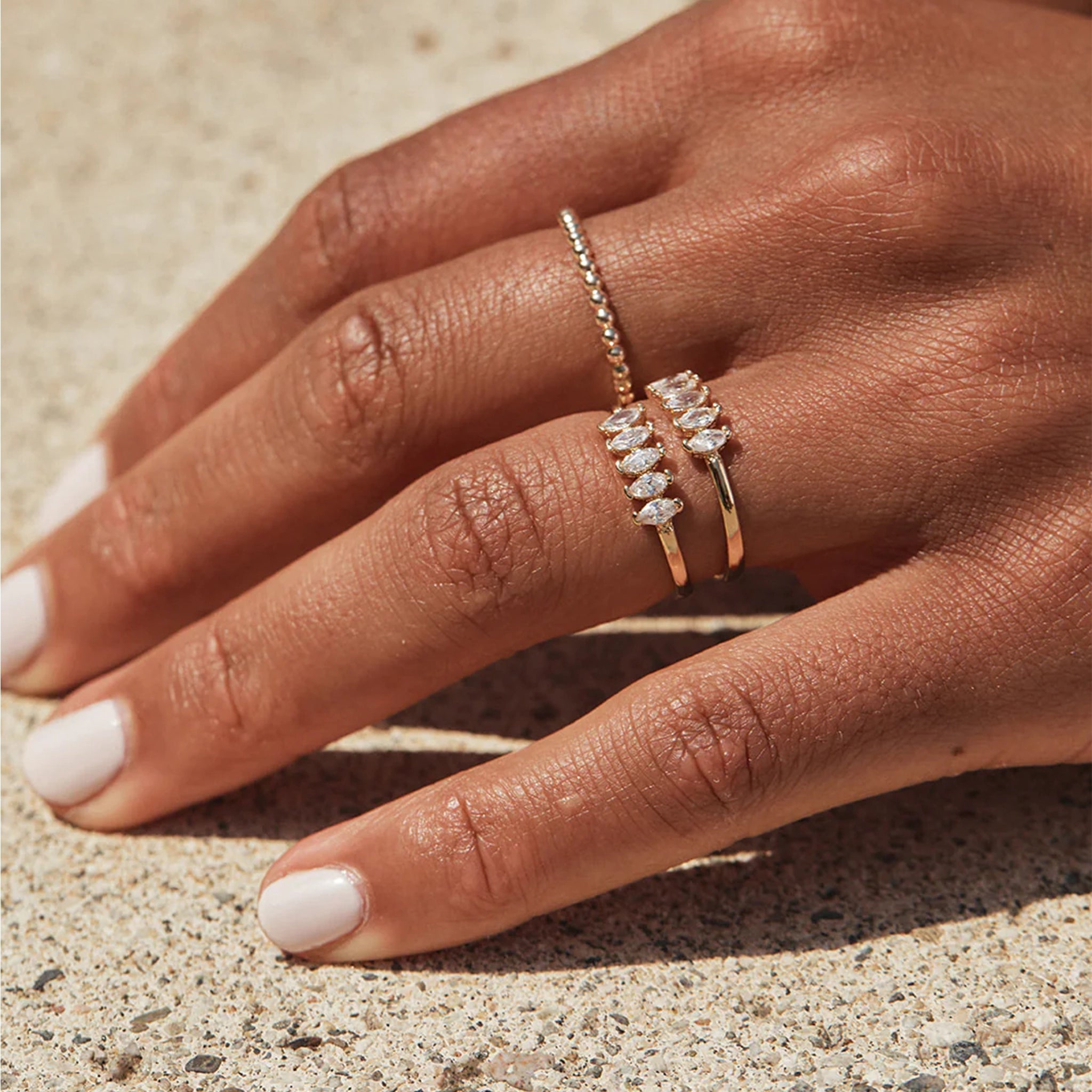 A model wearing the Cooper Ring which is a thin gold band with 5 cz diamonds stacked next to one another across the top. 