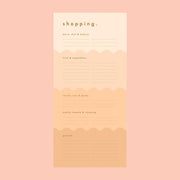 On a peachy background is a peachy wavy designed shopping notepad with gold foiled text details. 