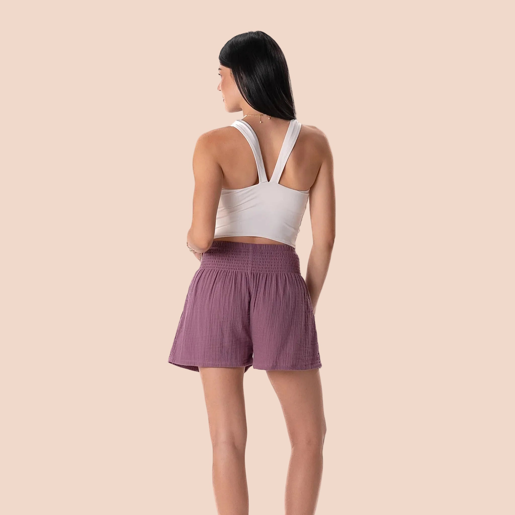 Woman wearing a white crop top and purple shorts on a white background