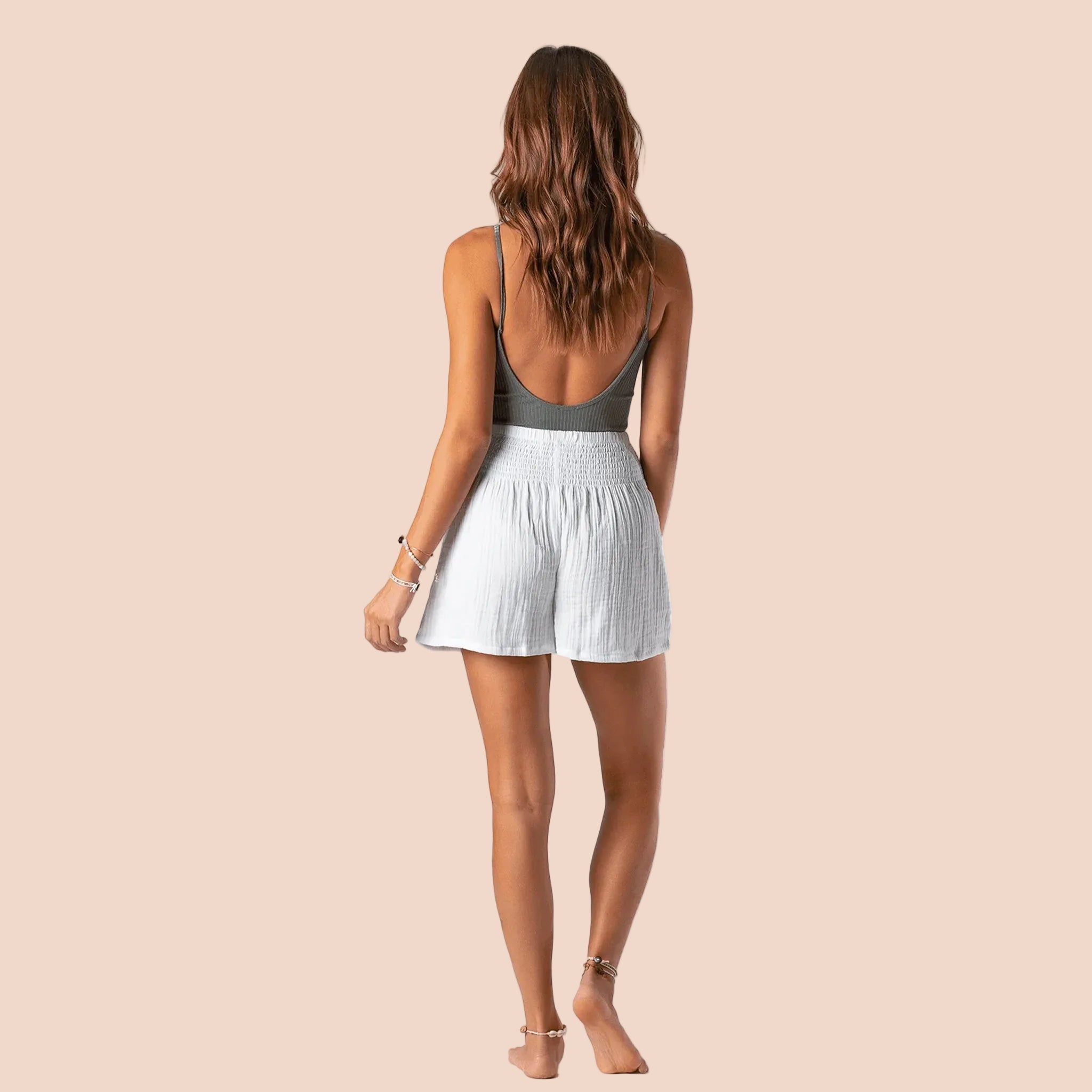 A model wearing a pair of white cotton shorts with an elastic waistband. 