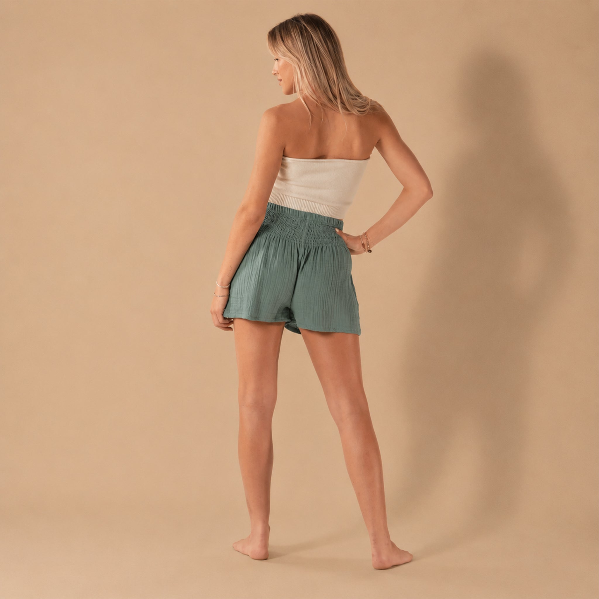 A model wearing a pair of green shorts with an elastic waistband.