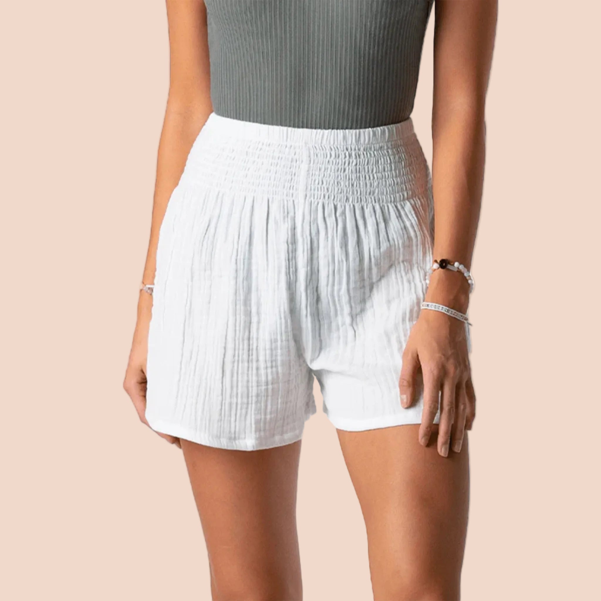 A model wearing a pair of white cotton shorts with an elastic waistband. 