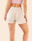 A pair of cream cotton shorts with an elastic waistband and a cotton linen material.