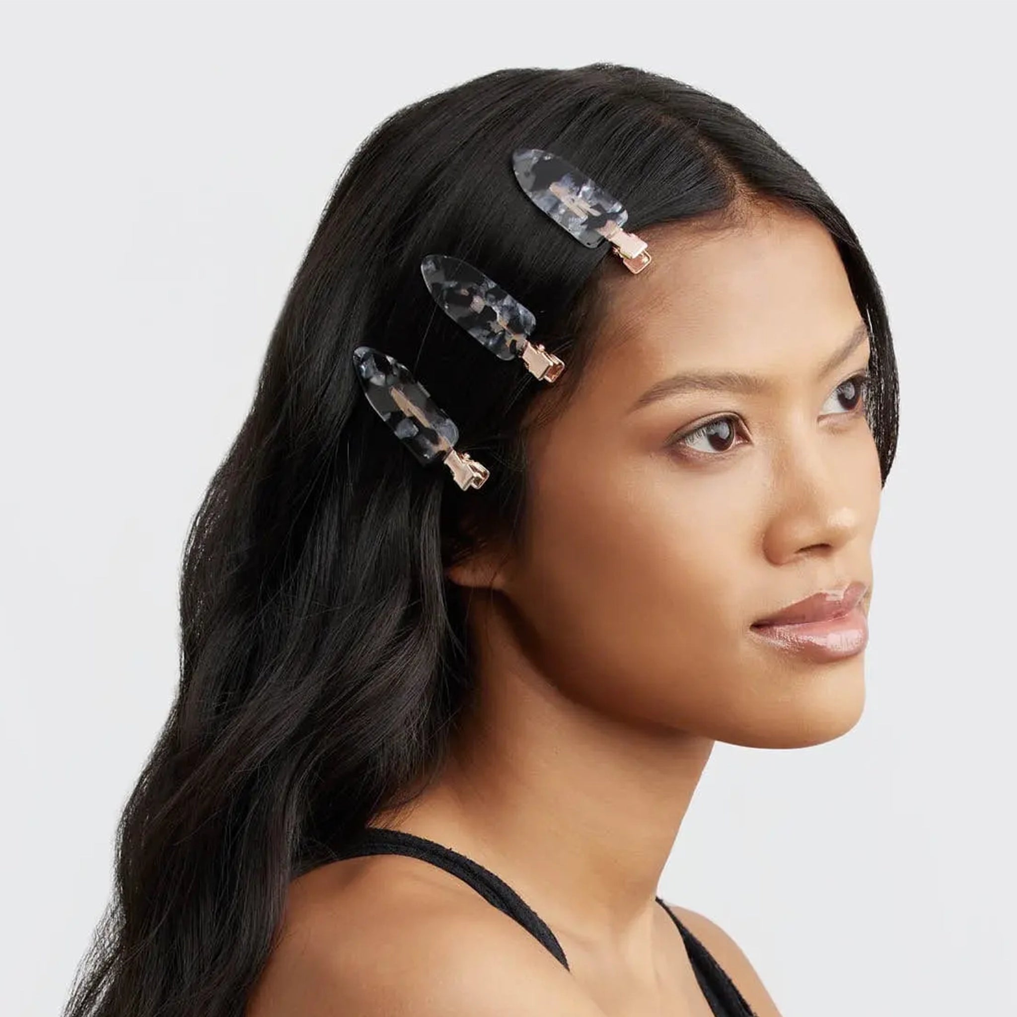 On a white background is a model wearing the creaseless clips with a black terrazzo print. 