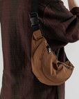 On a white background is a brown fanny pack with a front pocket with a black strap.