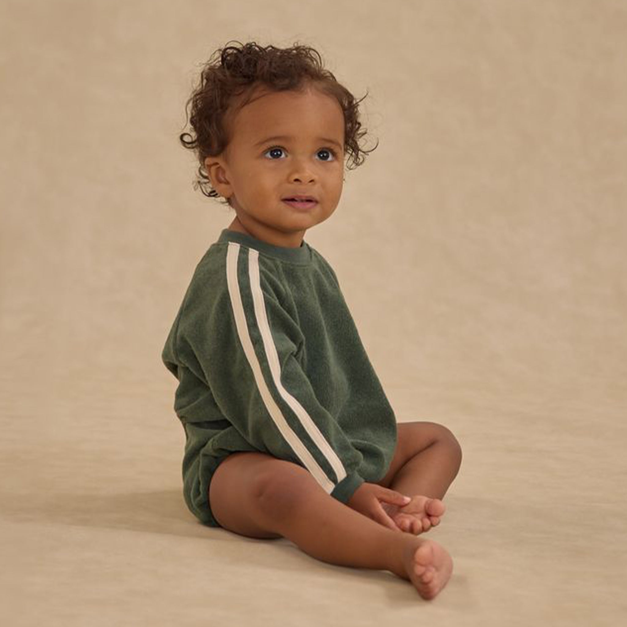 A green crewneck romper for babies with stripes down the sleeves. 