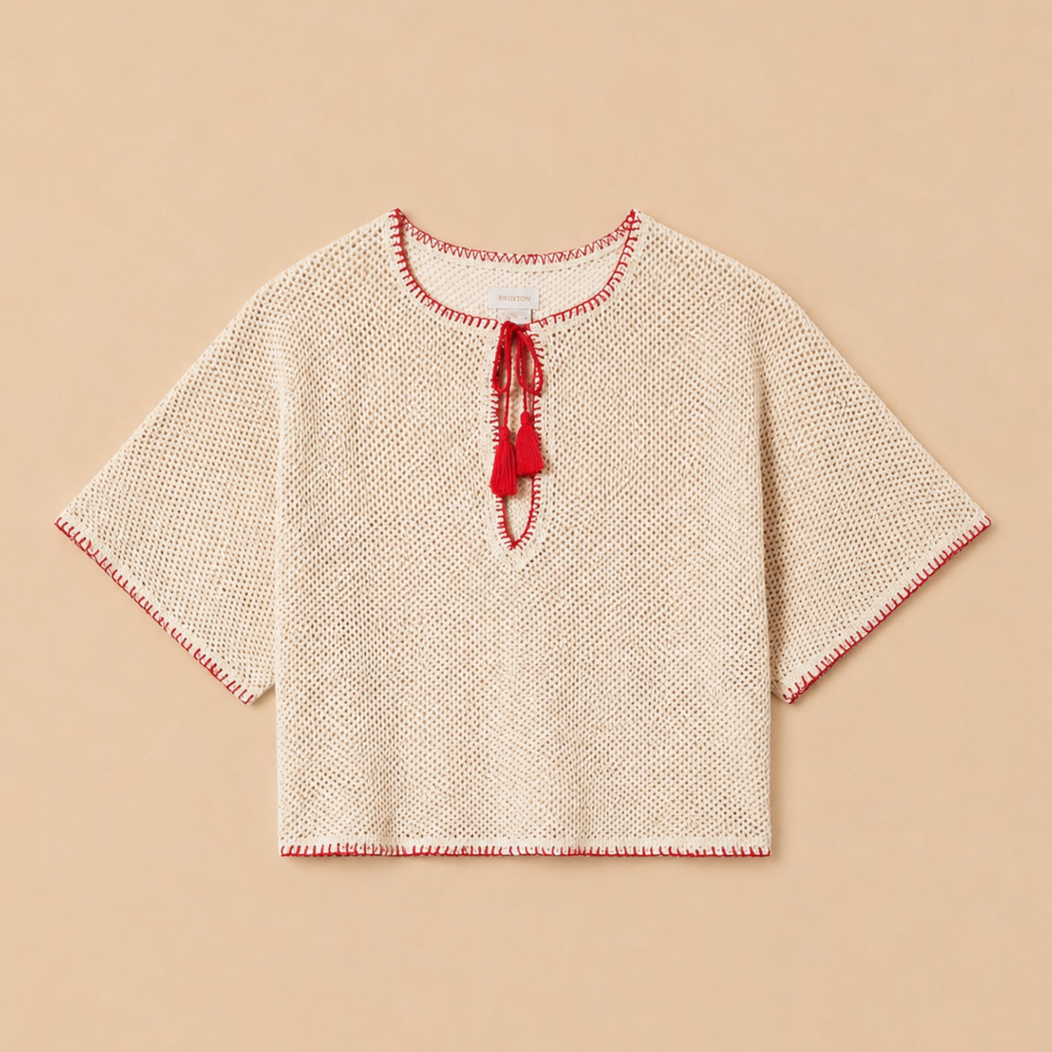 Beige knitted top with red trim on a beige background
