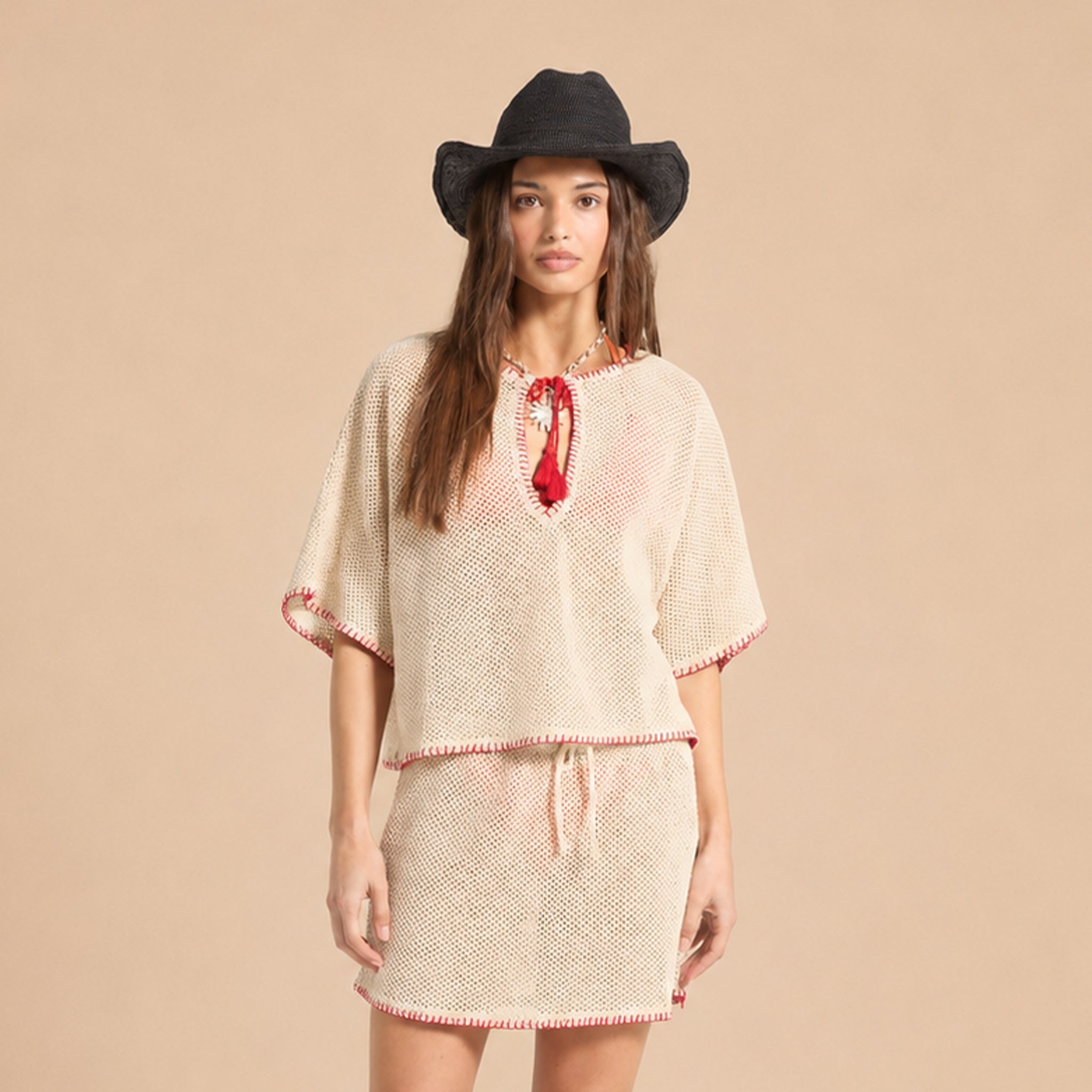 Beige knitted top with red trim on a beige background