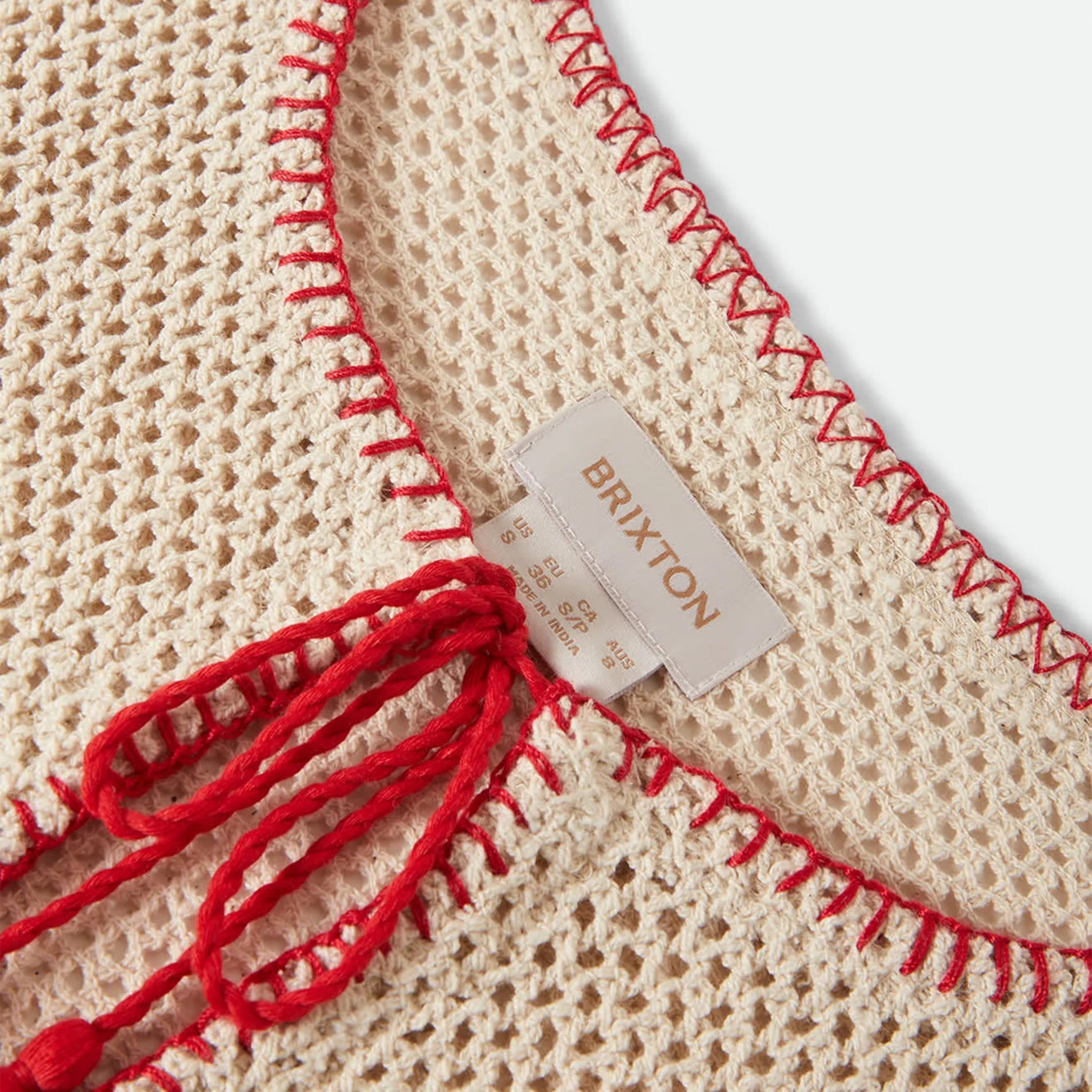 Beige knitted top with red trim on a beige background