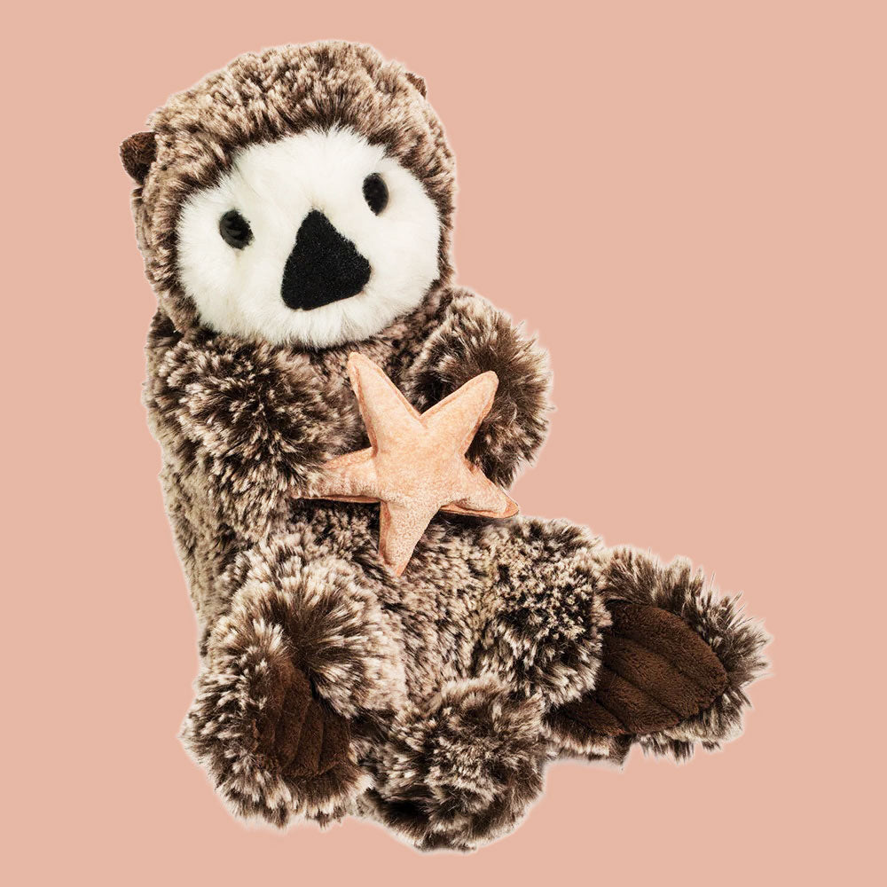 A grey and white otter stuffed animal that's holding a pink starfish. 