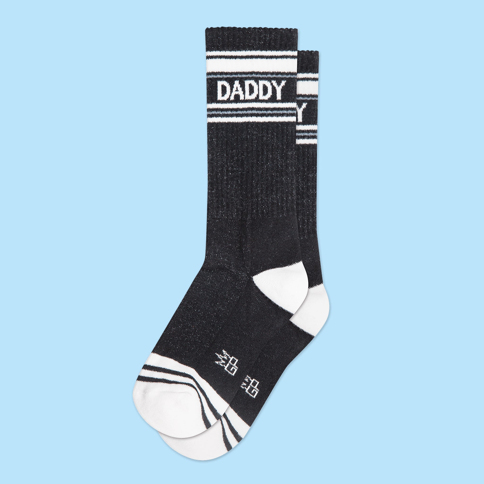 A pair of black and white crew socks that are ribbed with text across the top that reads, &quot;Daddy&quot;.