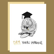 A white card with a graphic of a beaver wearing a graduation cap and black text that reads, 'Dam You're Impressive'. 
