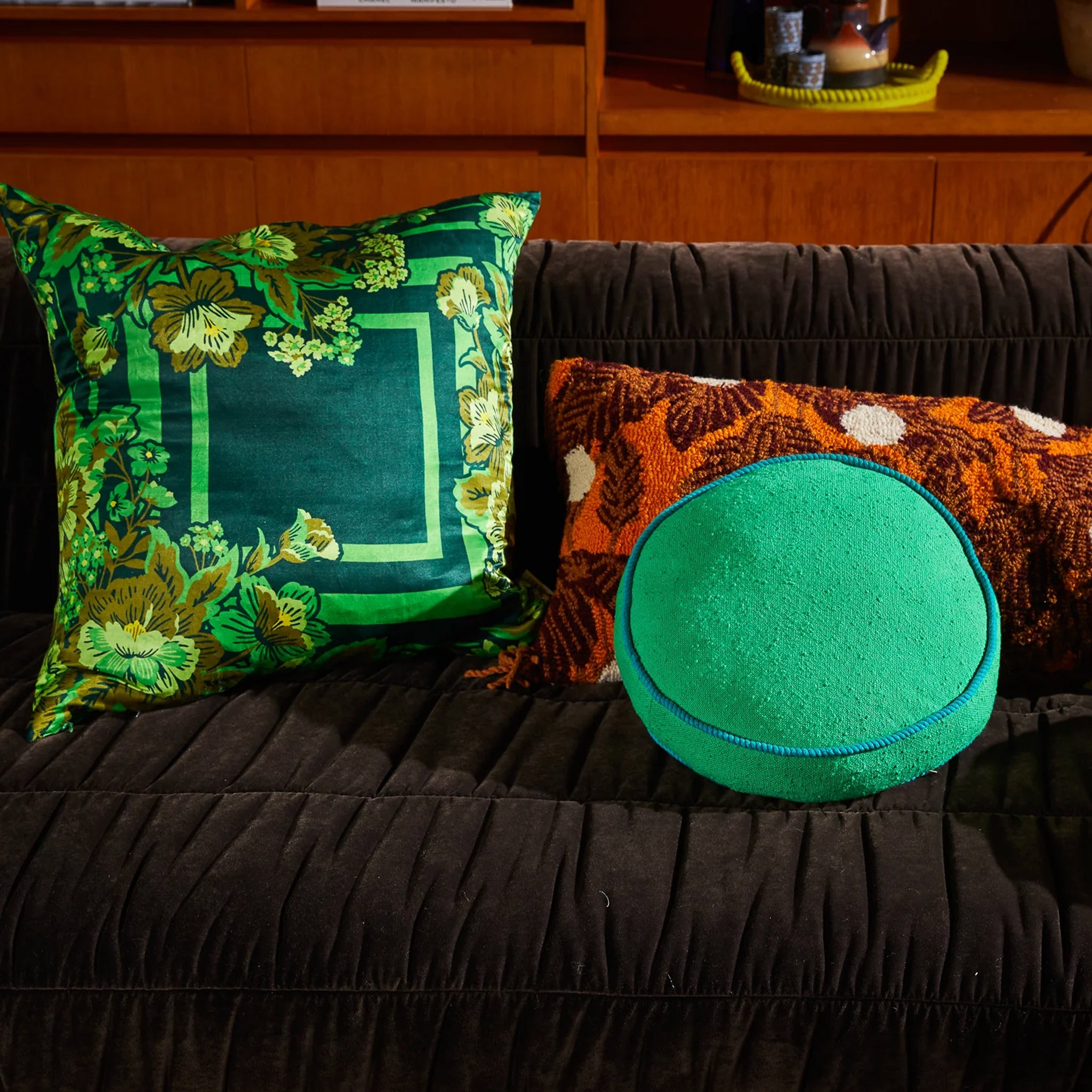 A green square cushion pillow with a floral print. 