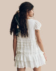 A white ruffle mini dress with a vneck and puff sleeves. 