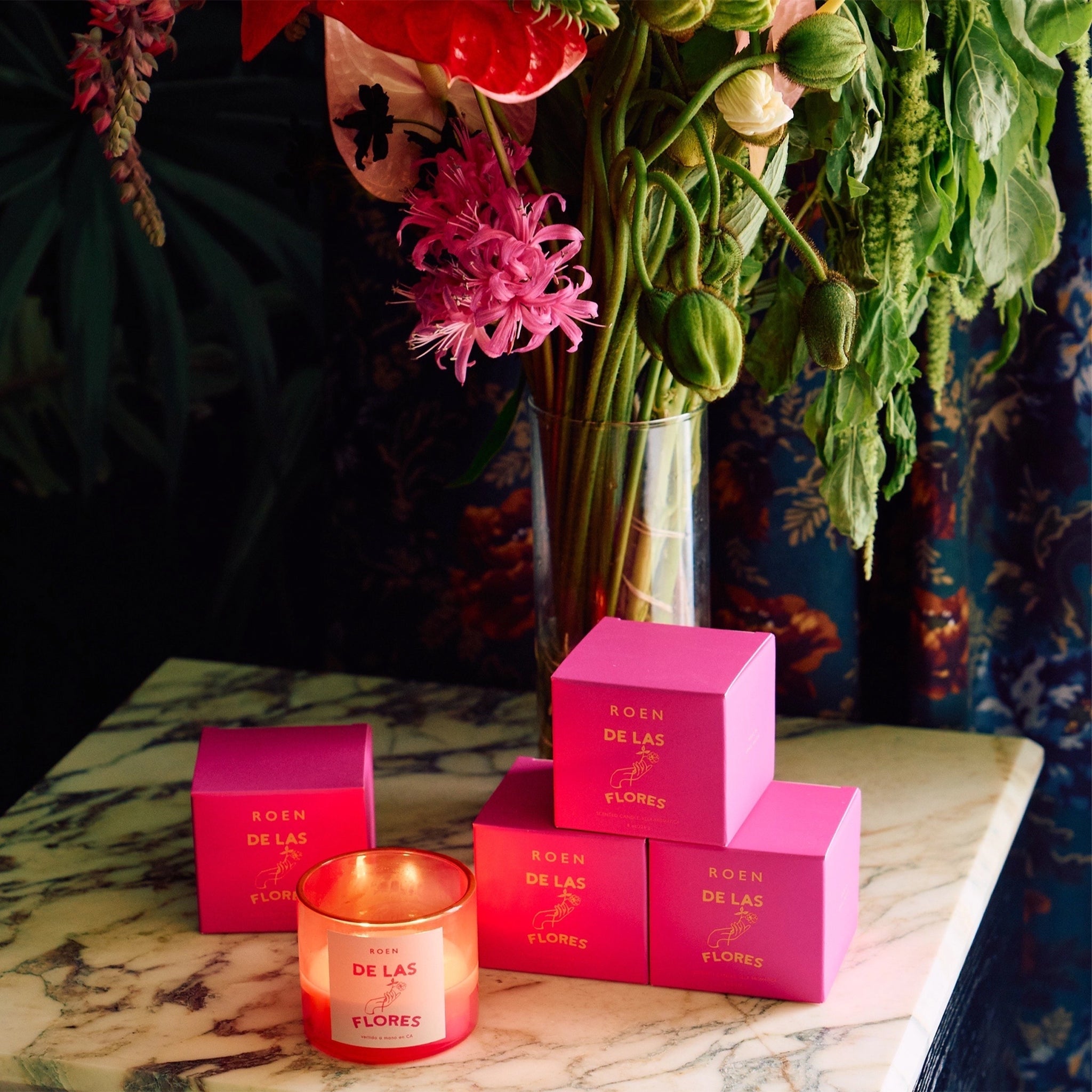 A hot pink glass candle with a label on the front that reads, "De Las Flores".