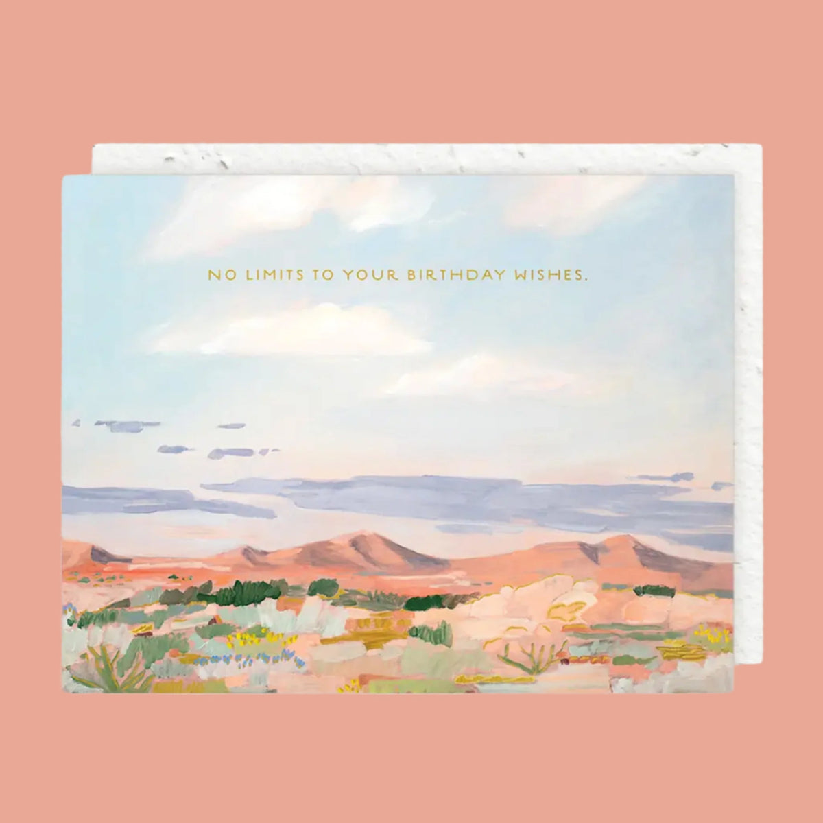 On a cream background is a greeting card with a desert, mountainous landscape illustration with earth tones along with text across the top that reads, "No Limits To Your Birthday Wishes".  