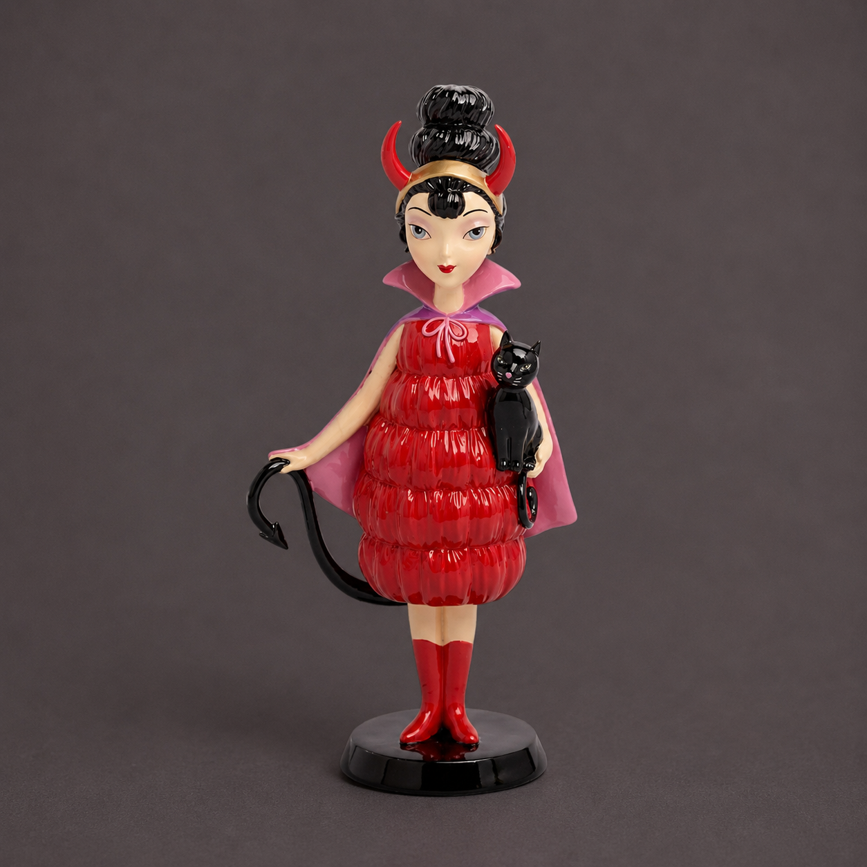 A mod girl figurine wearing a red devil outfit and holding a black cat. 