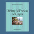 A blue box of a puzzle with a photo of people gathered at a family style table eating a spread of Italian food overlooking the coastline. 