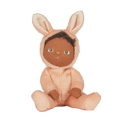 On a white background is a doll with a pink rabbit fuzzy onesie on that has bunny ears. 