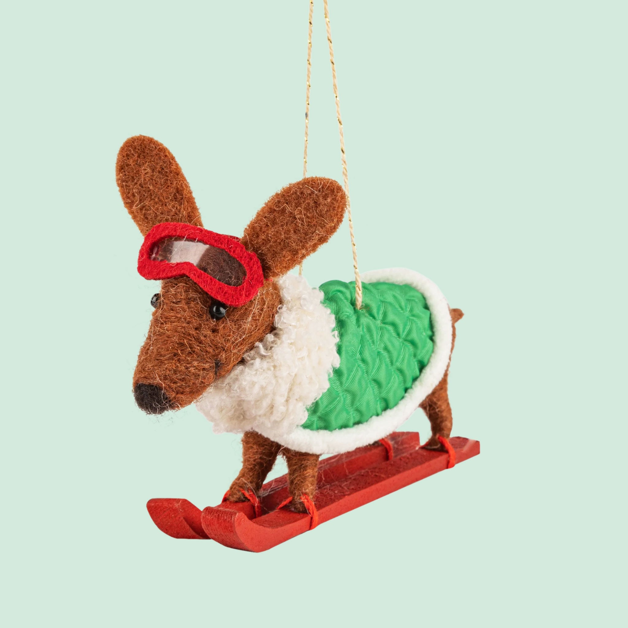 A brown dachshund shaped ornament on skis and wearing a green jacket. 