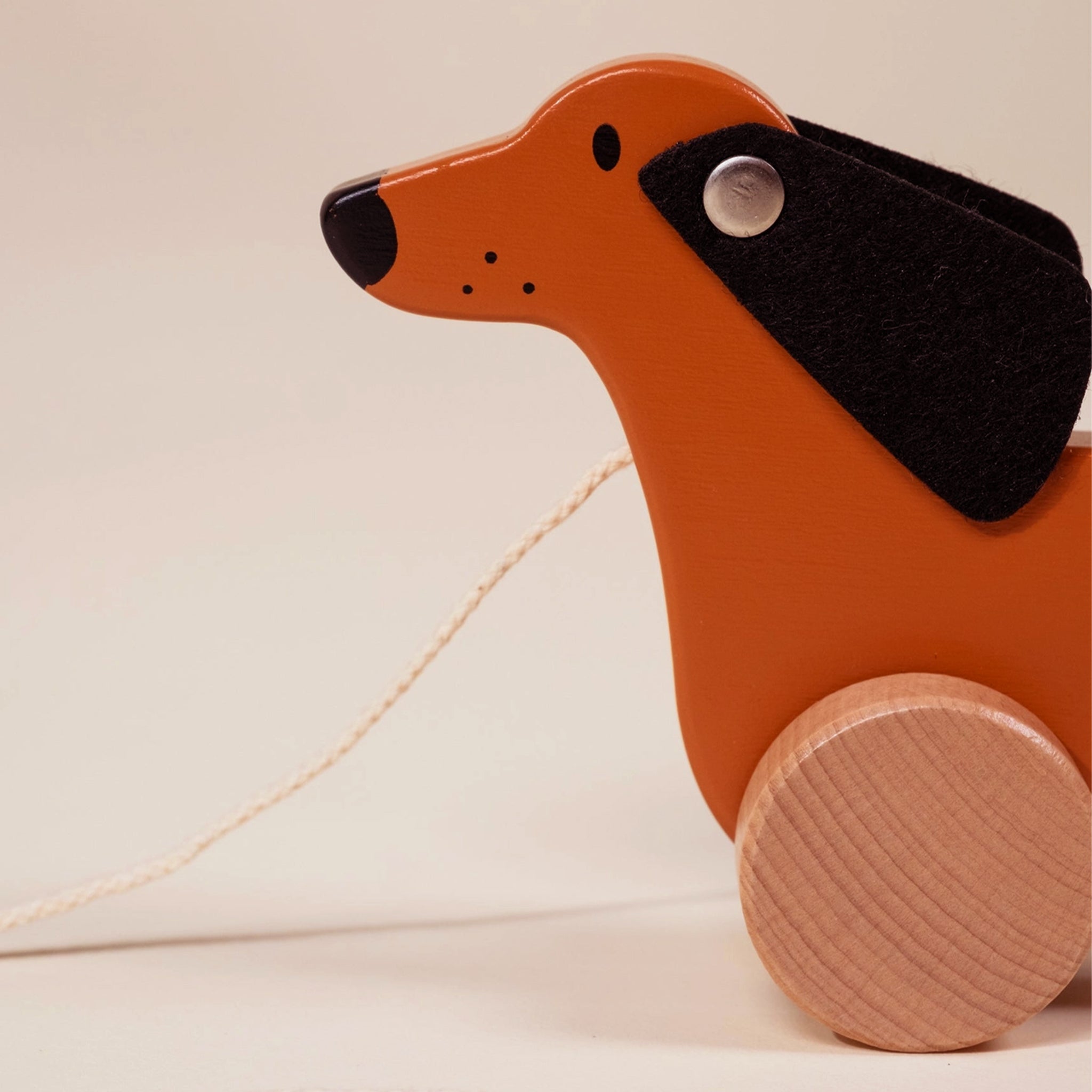 A wooden dog shaped pull toy with wooden wheels. 