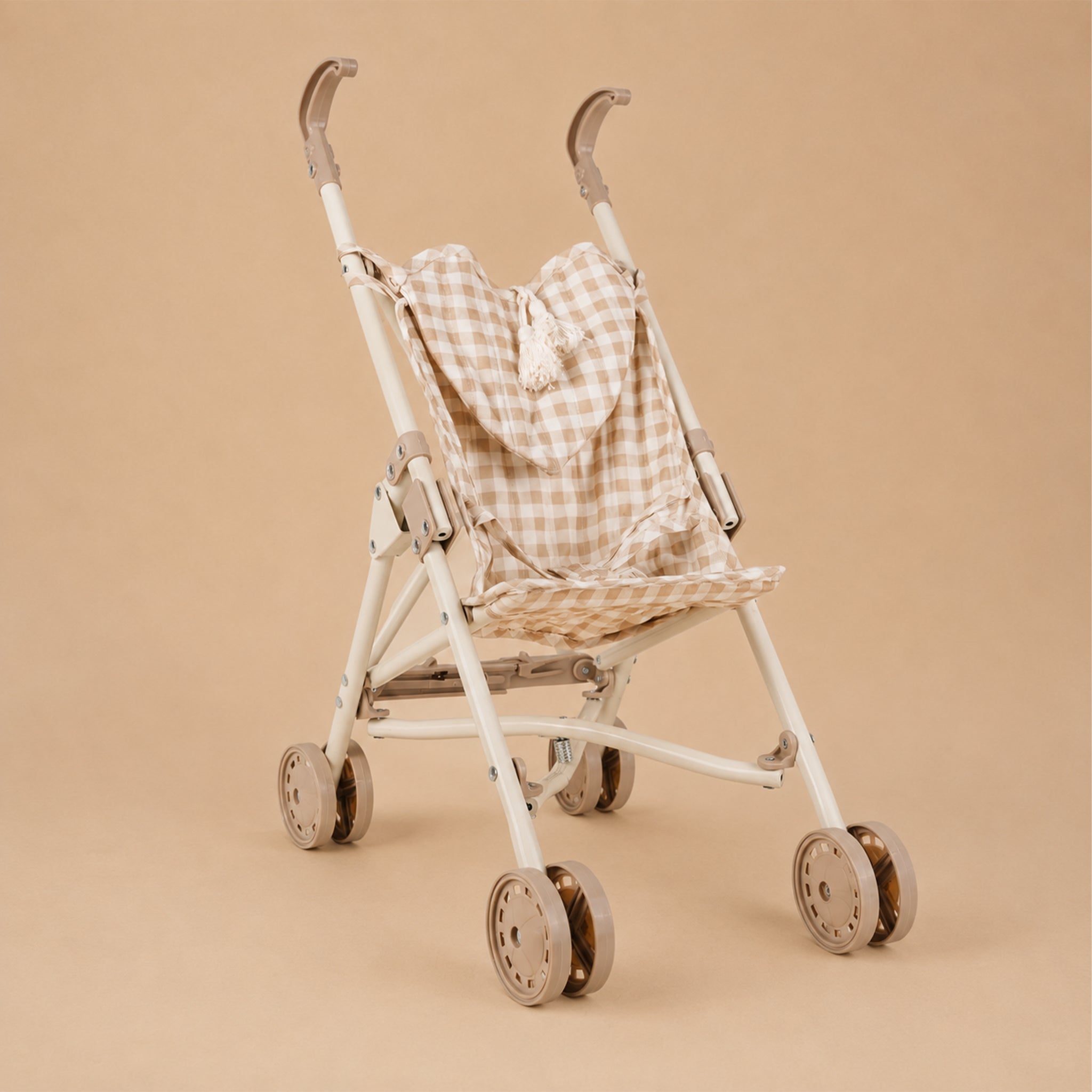 White baby stroller with a checkered cover on a beige background