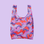 A reusable bag with red, pink and purple dolphins and details on a lavender background.