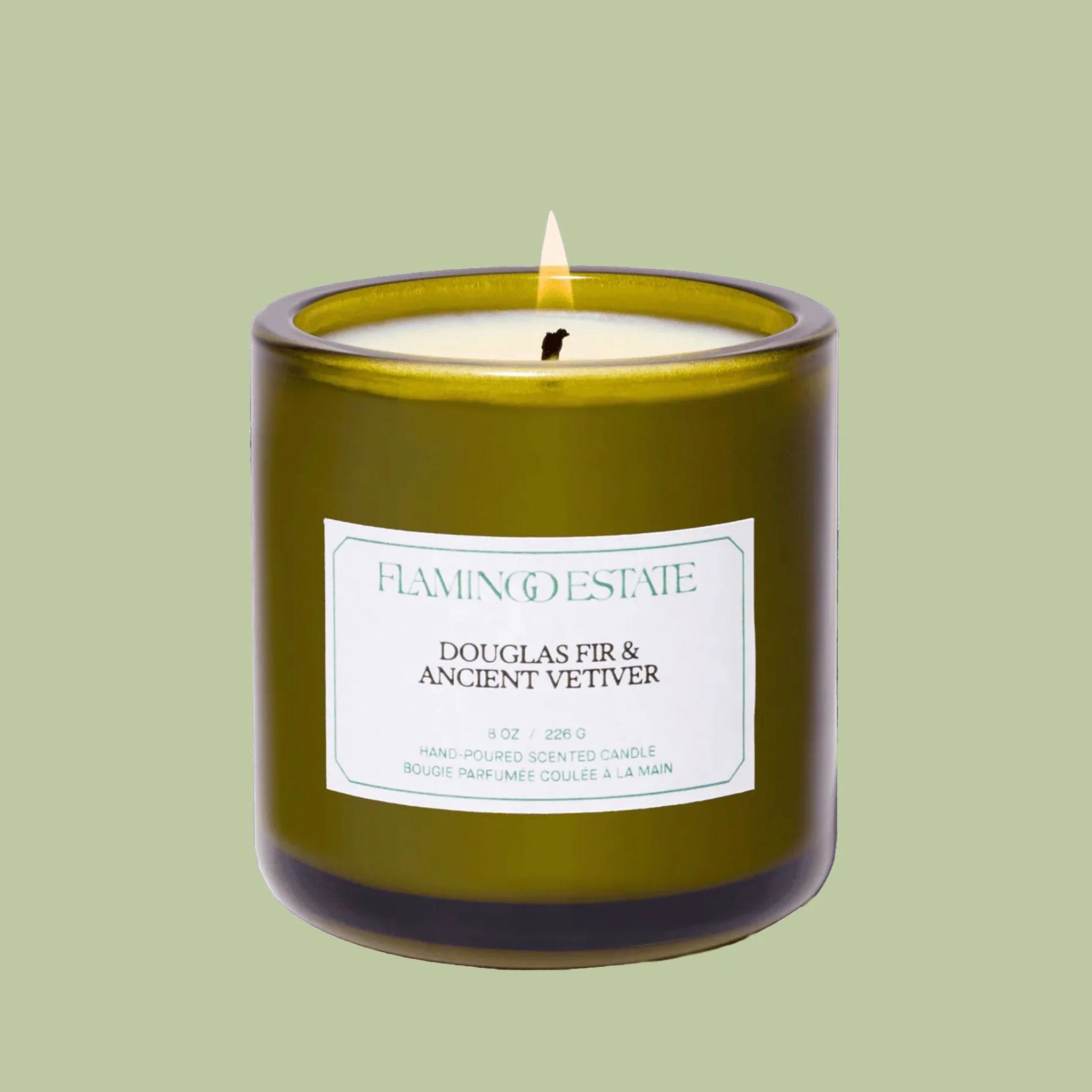 A green glass candle with a white label in the center. 