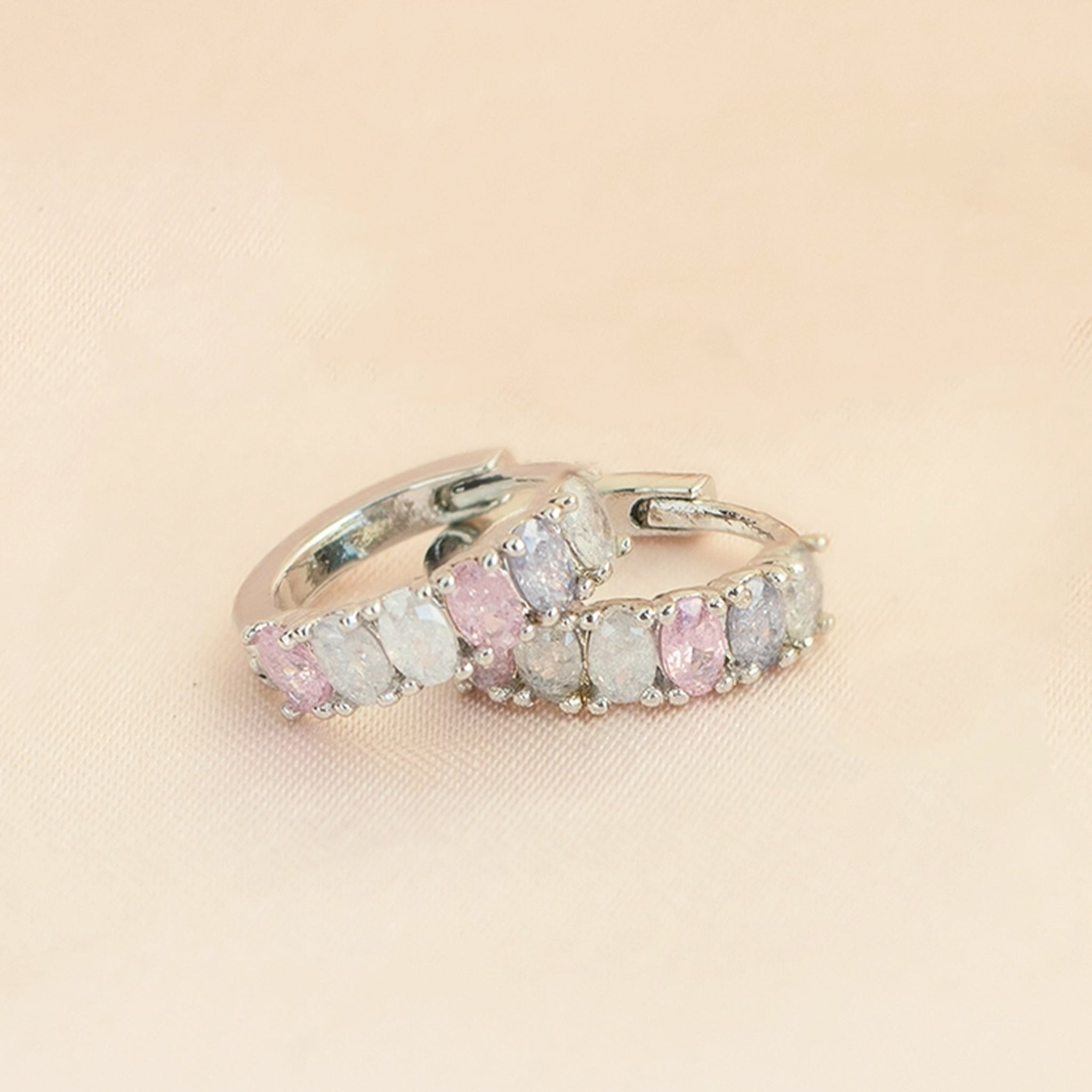 A silver pair of hoops with white, clear, pink and light purple cz stones across the top. 