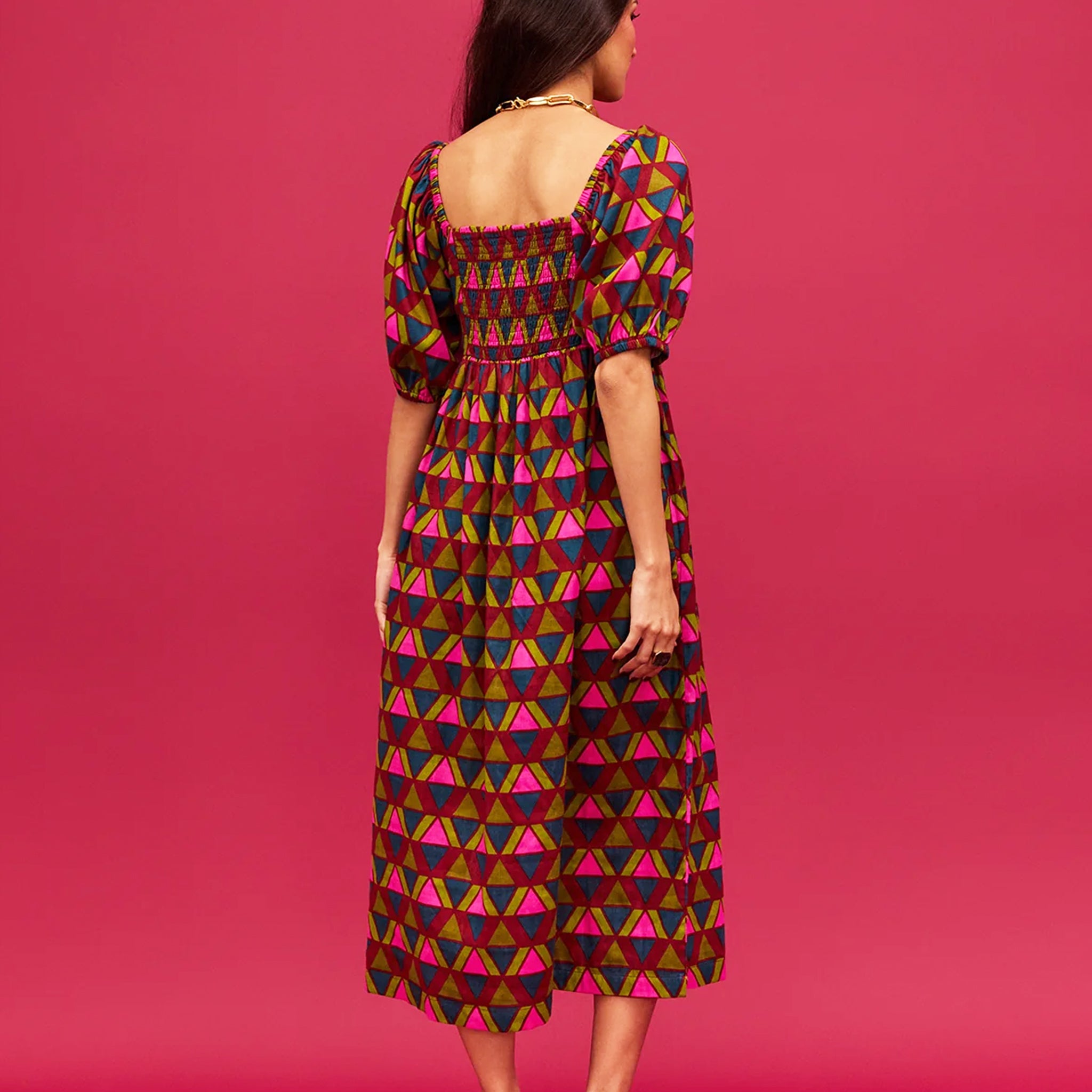 A pink, green, teal and red triangle patterned maxi dress with a square neckline, pockets and puff sleeves.
