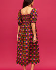 A pink, green, teal and red triangle patterned maxi dress with a square neckline, pockets and puff sleeves.
